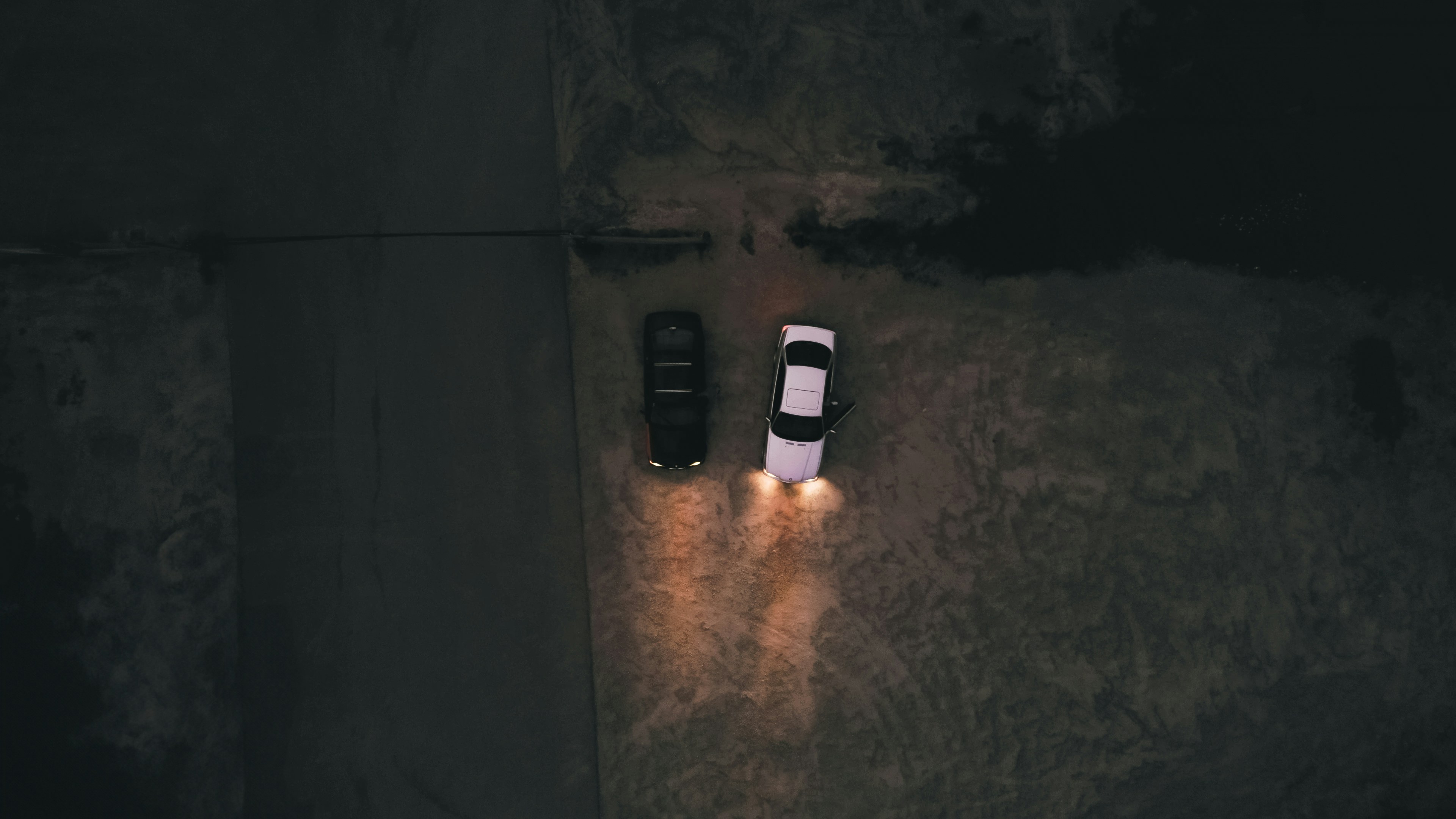 two cars parked in a parking lot at night