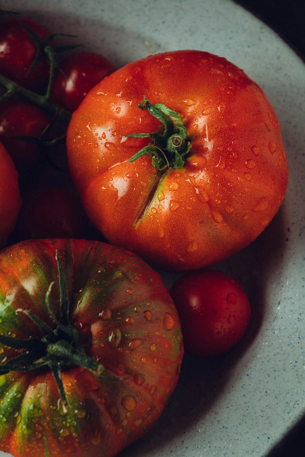 a bowl of tomatoes with water droplets on them