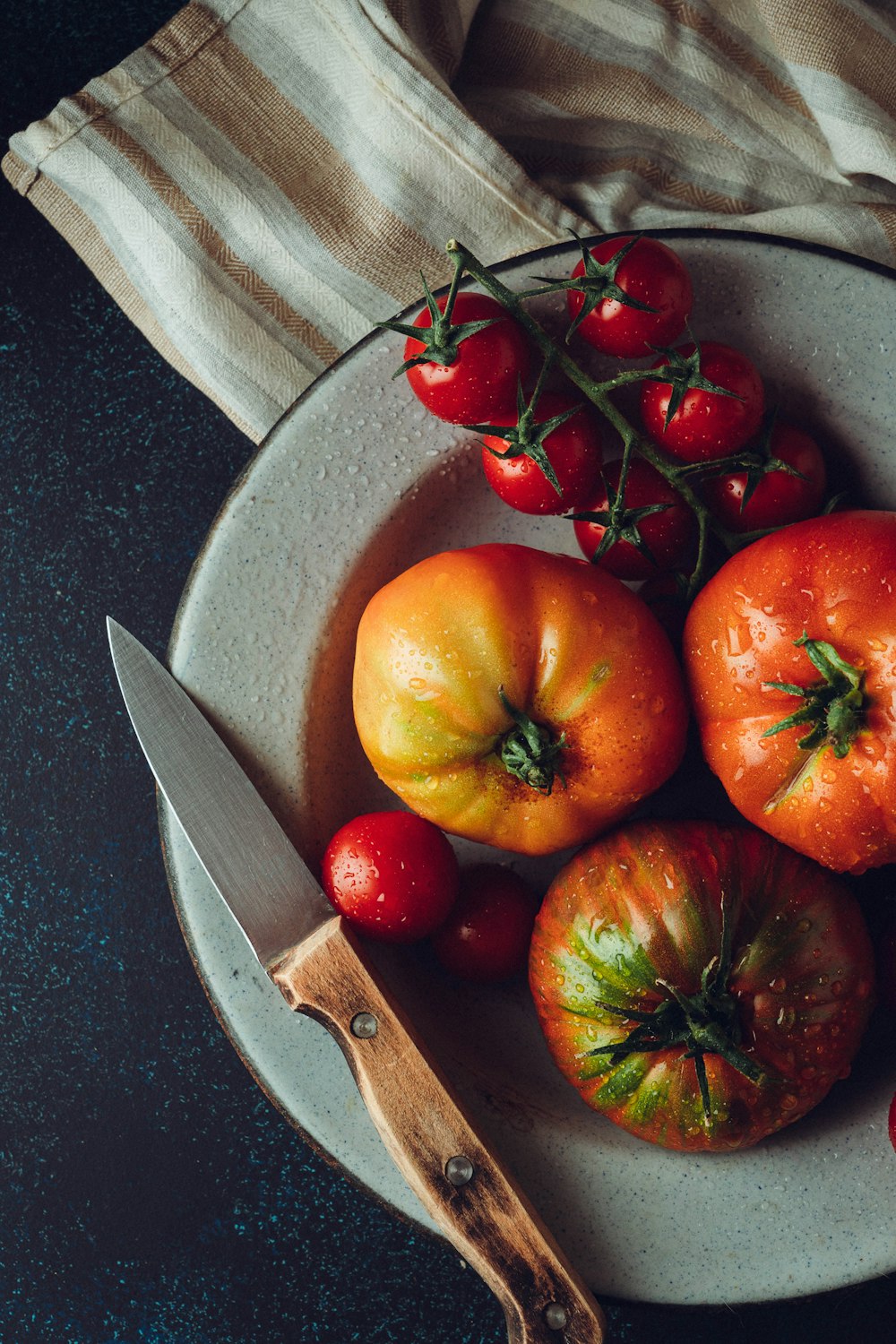 a white plate topped with tomatoes and a knife