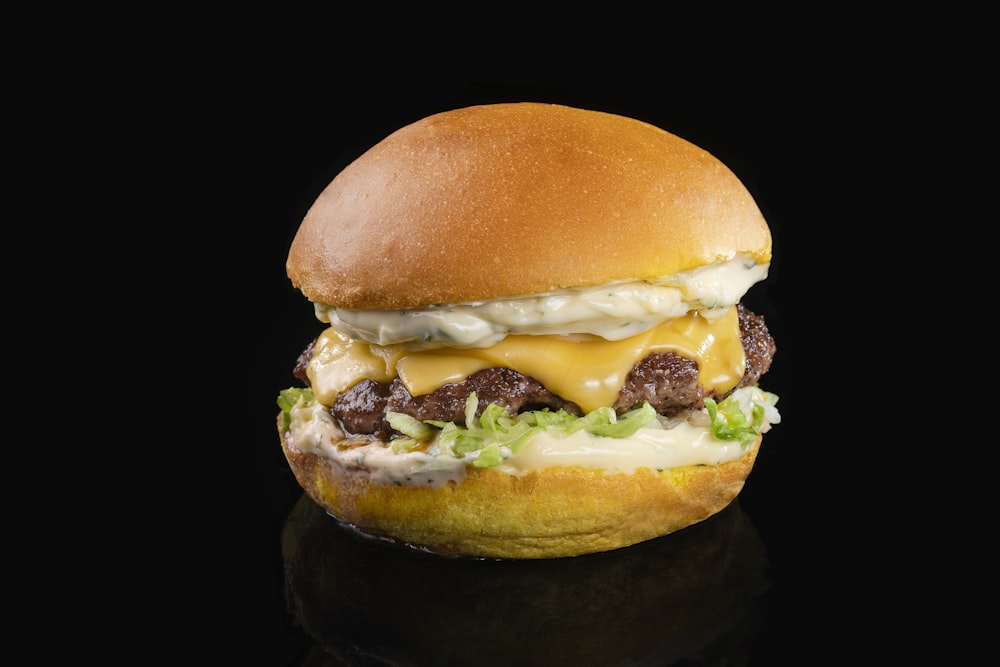 a cheeseburger with meat and lettuce on a black background