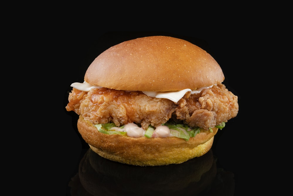 a chicken sandwich with lettuce and mayonnaise on a black background