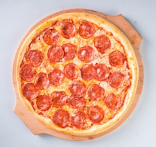a pepperoni pizza sitting on top of a wooden cutting board