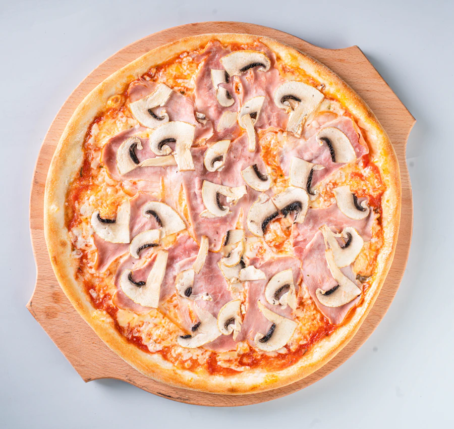 Pizza with ham and mushrooms on a wooden board