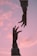 two hands reaching towards each other in front of a pink sky
