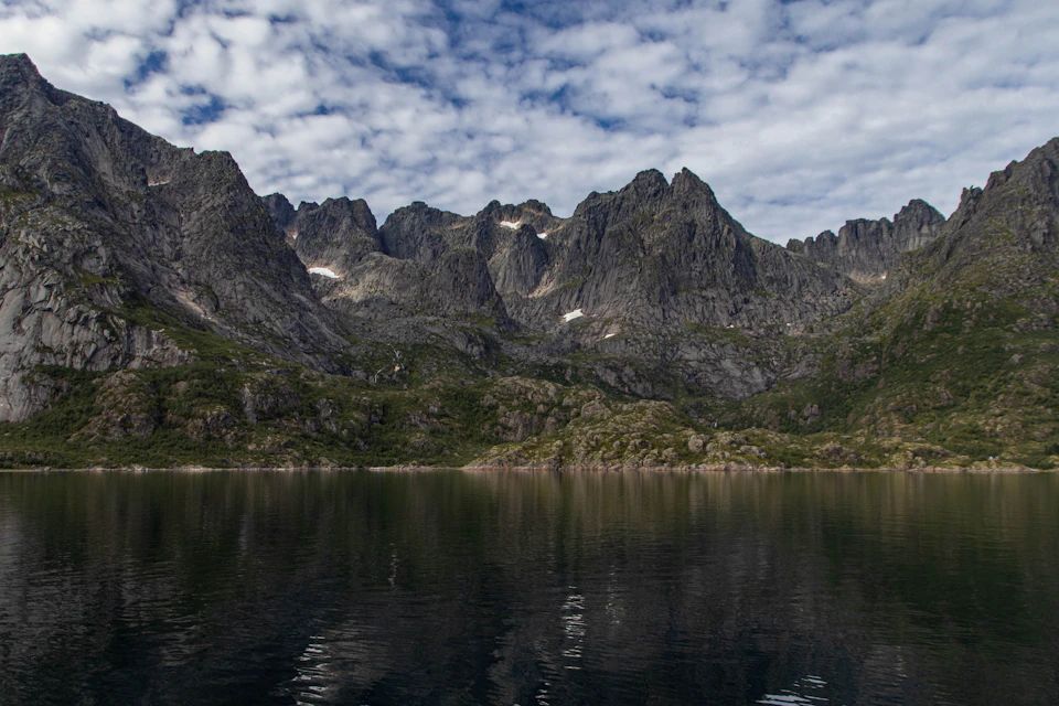 Serene mountain landscape with lake at its base, surrounded by towering mountains and vegetation