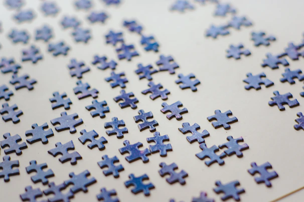 A colorful flat puzzle spread out on a wooden table with scattered irregular pieces waiting to be assembled.
