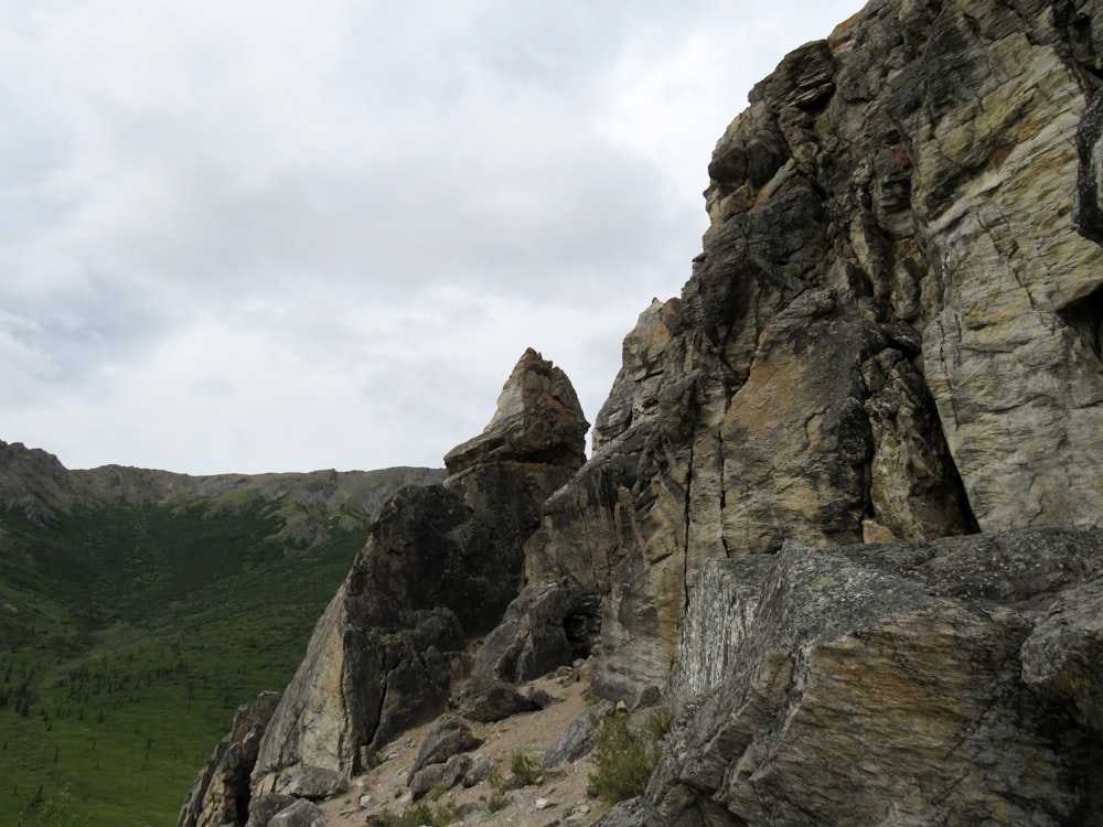 a rocky cliff with a green valley in the background