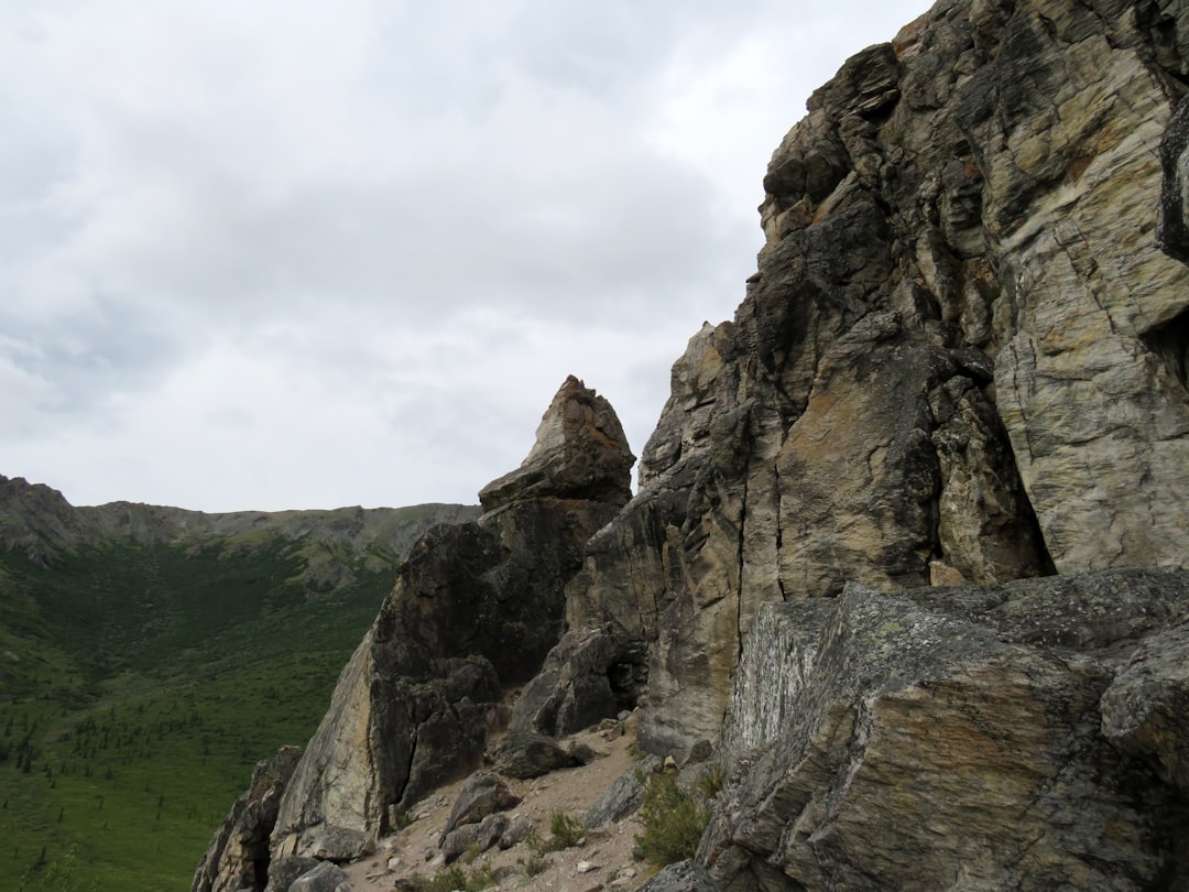 a rocky cliff with a green valley in the background,