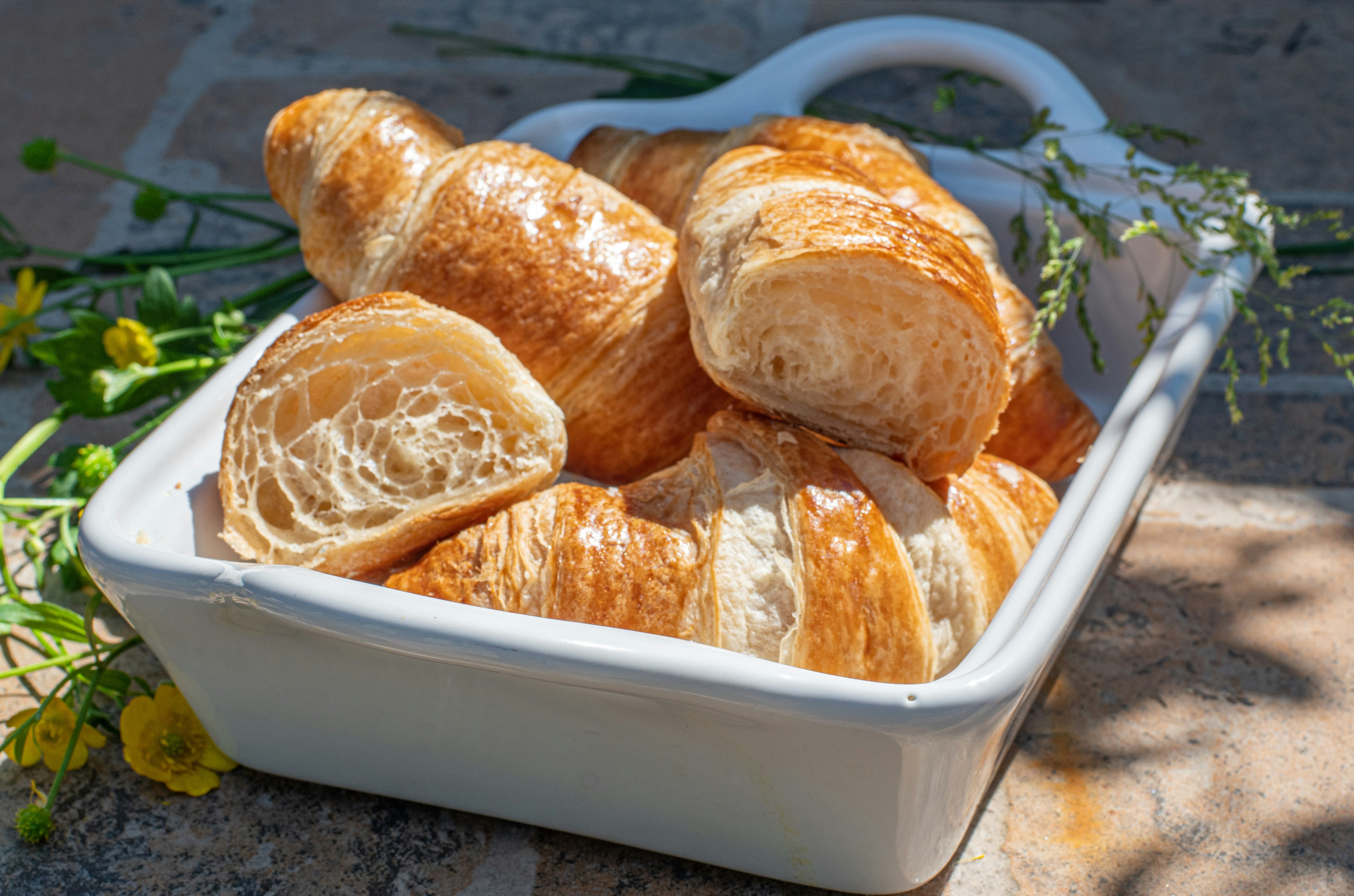 a white dish filled with croissants sitting on top of a stone floor