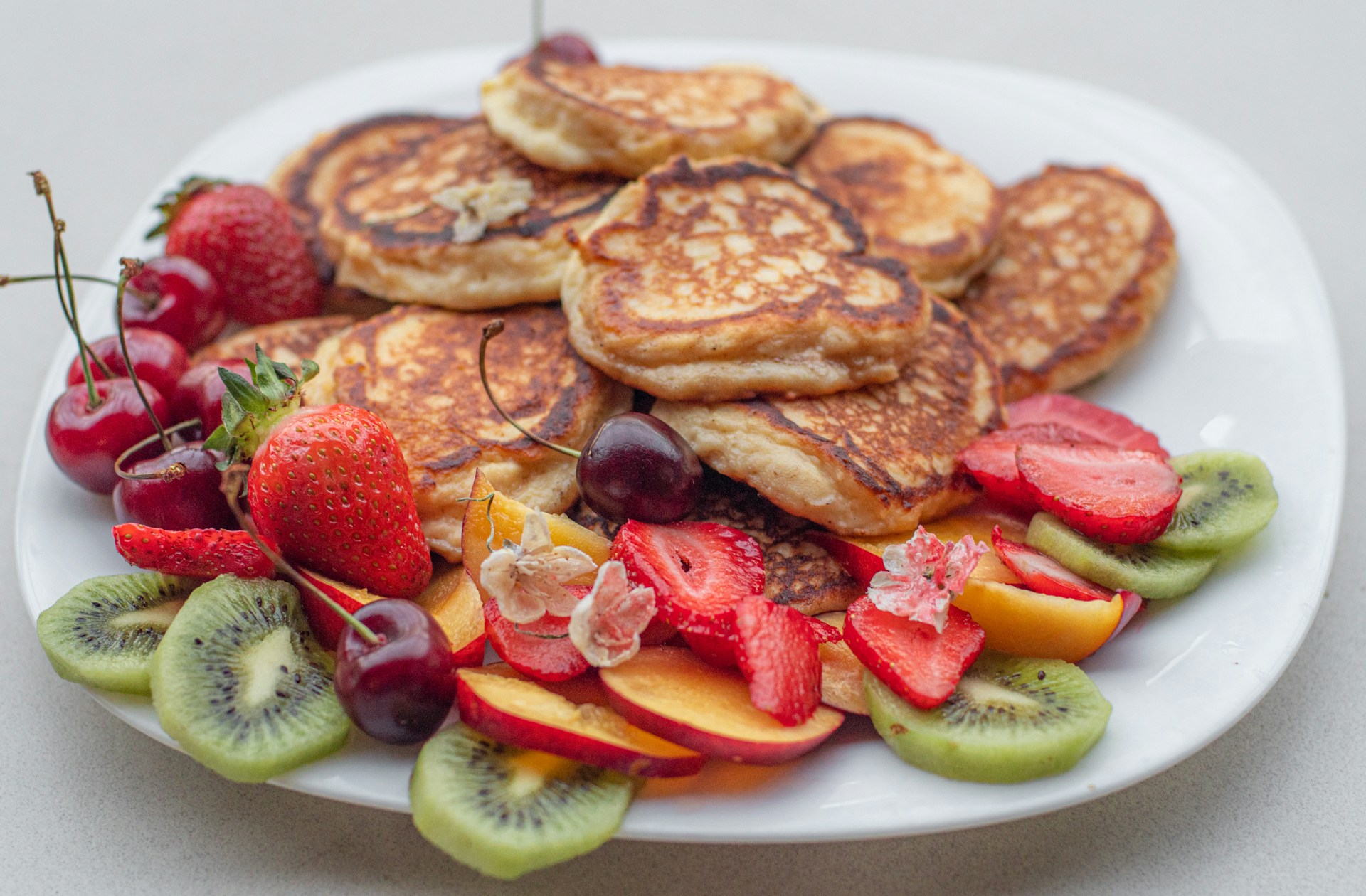 A stack of gourmet pancakes topped with fresh fruits and syrup, highlighting the delicious breakfast options.