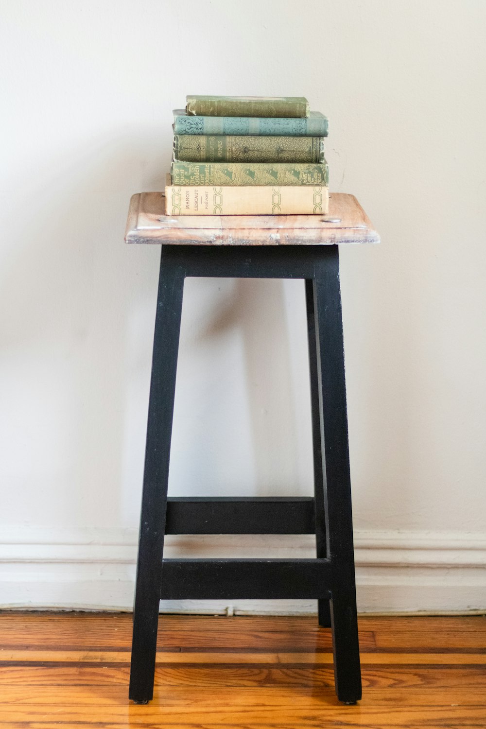 a stack of books sitting on top of a wooden stool