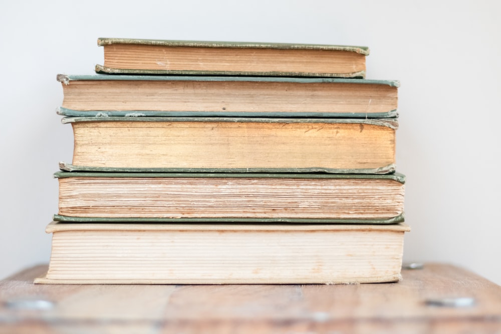 a stack of books sitting on top of a wooden table