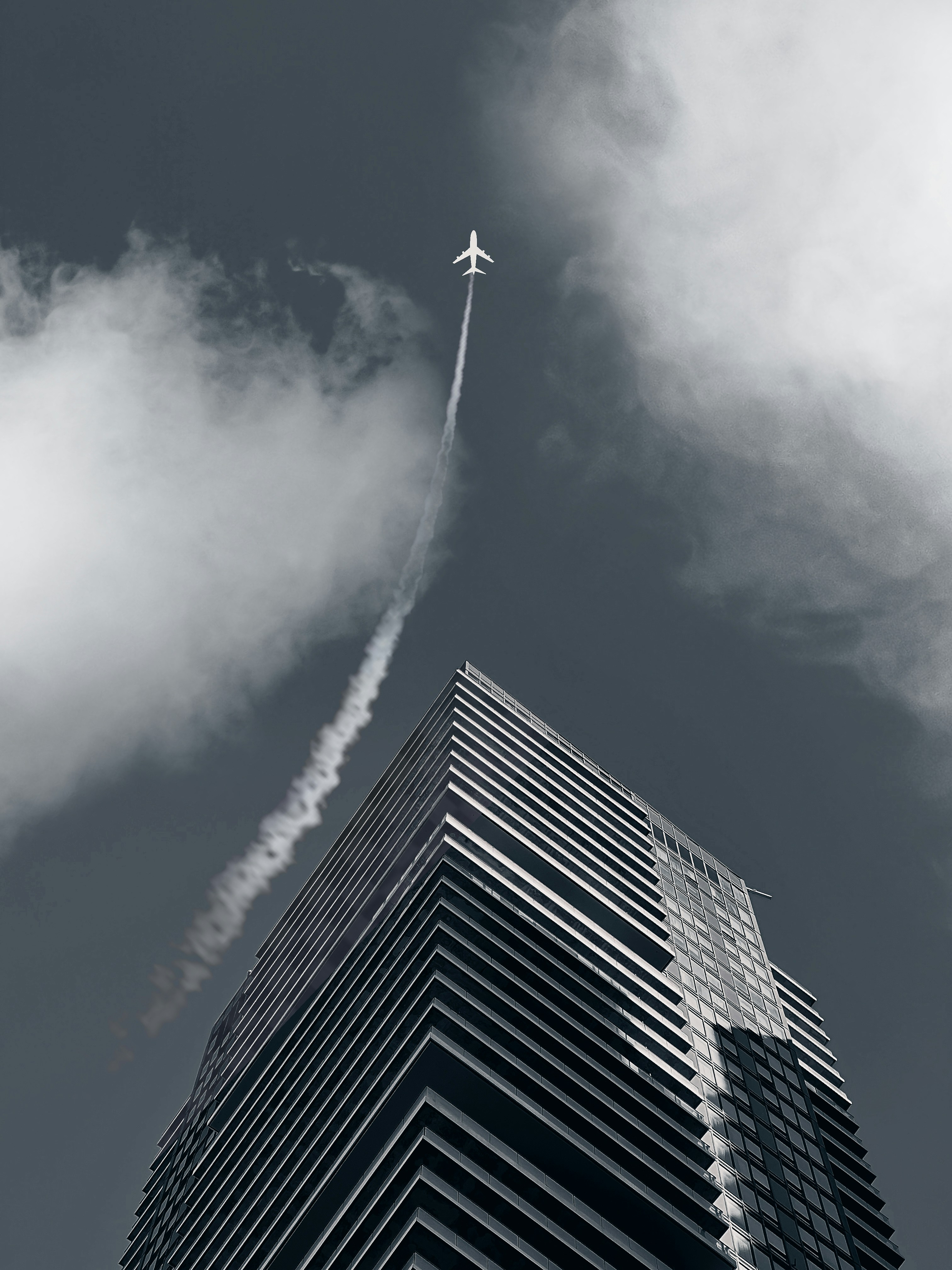 a plane flying in the sky over a tall building