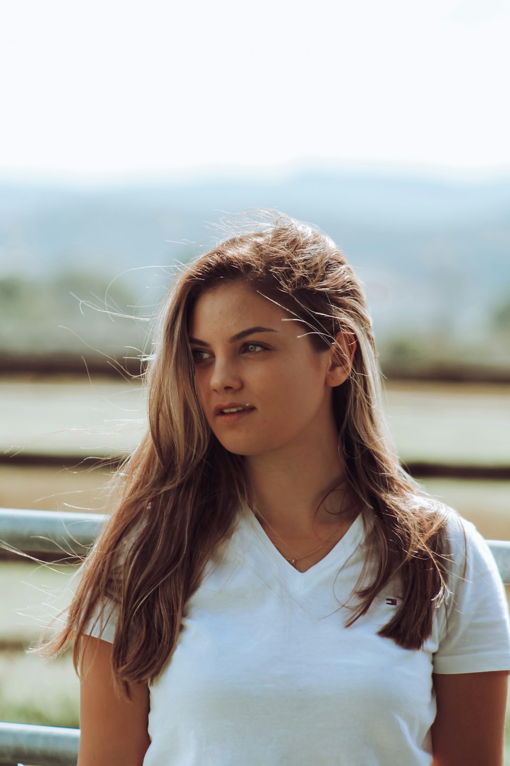 a woman with long hair standing in front of a fence