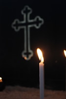 A quiet candle burning beside a cross, symbolizing hope and transformation.