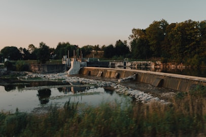 A serene hydroelectric dam nestled in a lush green valley during sunrise.