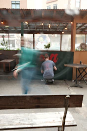 A craftsman carefully painting a vibrant crimson signboard in a cozy workshop filled with natural light.