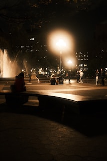 A serene public square with a modern water fountain gently flowing under soft evening lights.