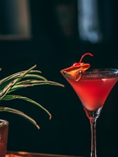 A vibrant cocktail glass filled with a colorful drink garnished with herbs.