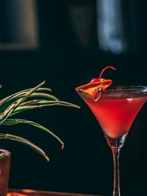 A vibrant cocktail glass filled with a colorful drink garnished with herbs.