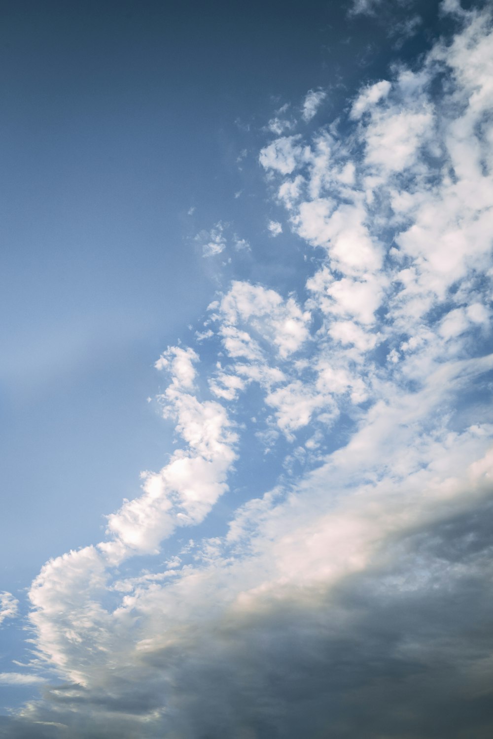 a plane flying through a cloudy blue sky