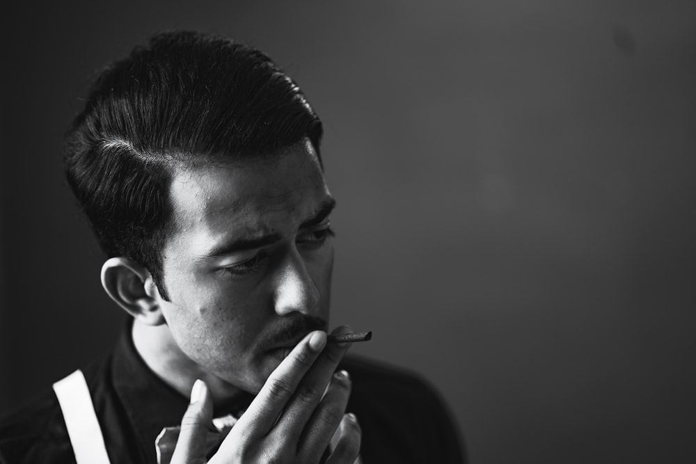 a man is smoking a cigarette in a black and white photo