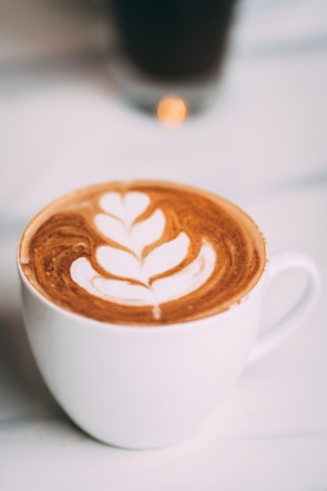 Close-up of a freshly brewed cappuccino with delicate latte art on cream-colored ceramic.