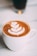 A close-up of a steaming cup of cappuccino with delicate latte art on top.