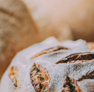 Close-up of a rustic artisan sourdough loaf with a golden crust resting on a wooden board dusted with flour.