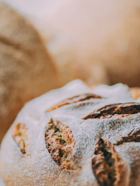 Close-up of freshly baked artisan bread with golden crust on a rustic wooden table.