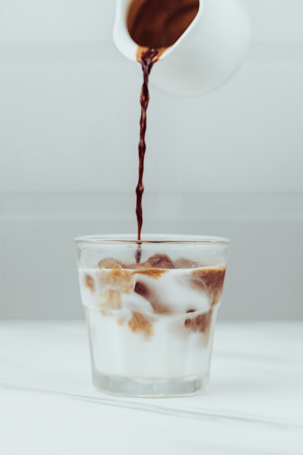 a cup of coffee being poured into a glass