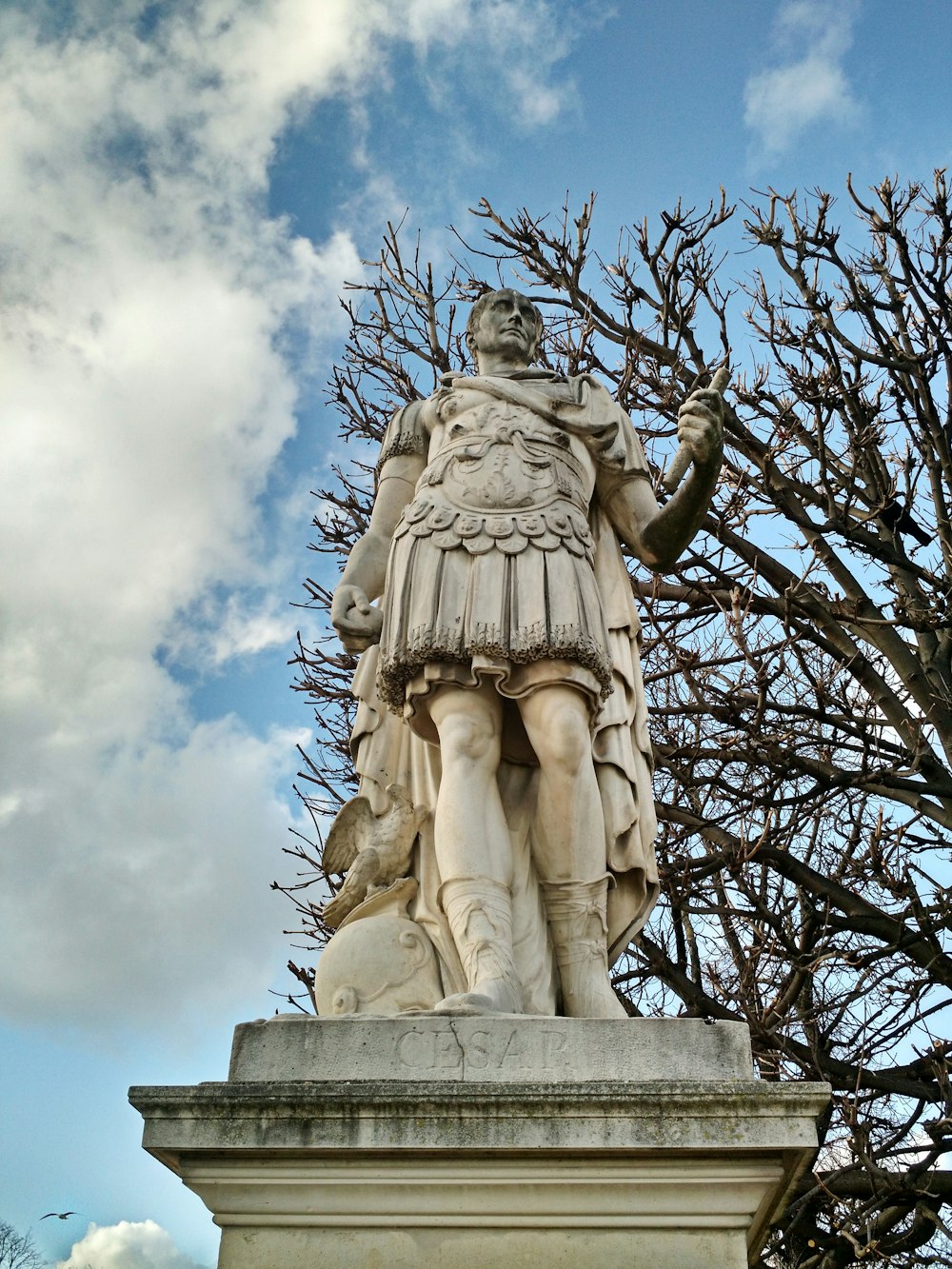 a statue of a man standing next to a tree