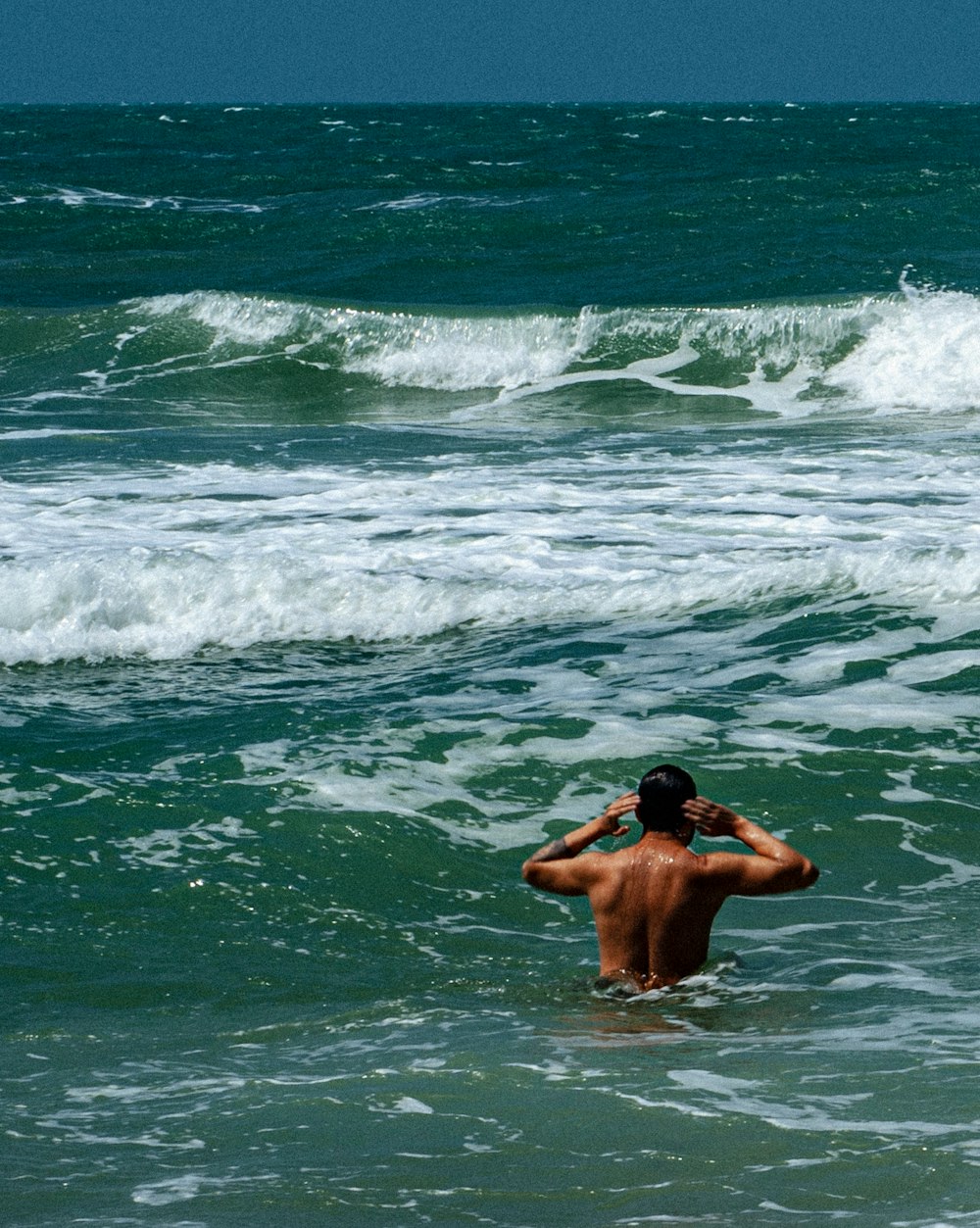 a man standing in the ocean with his back to the camera