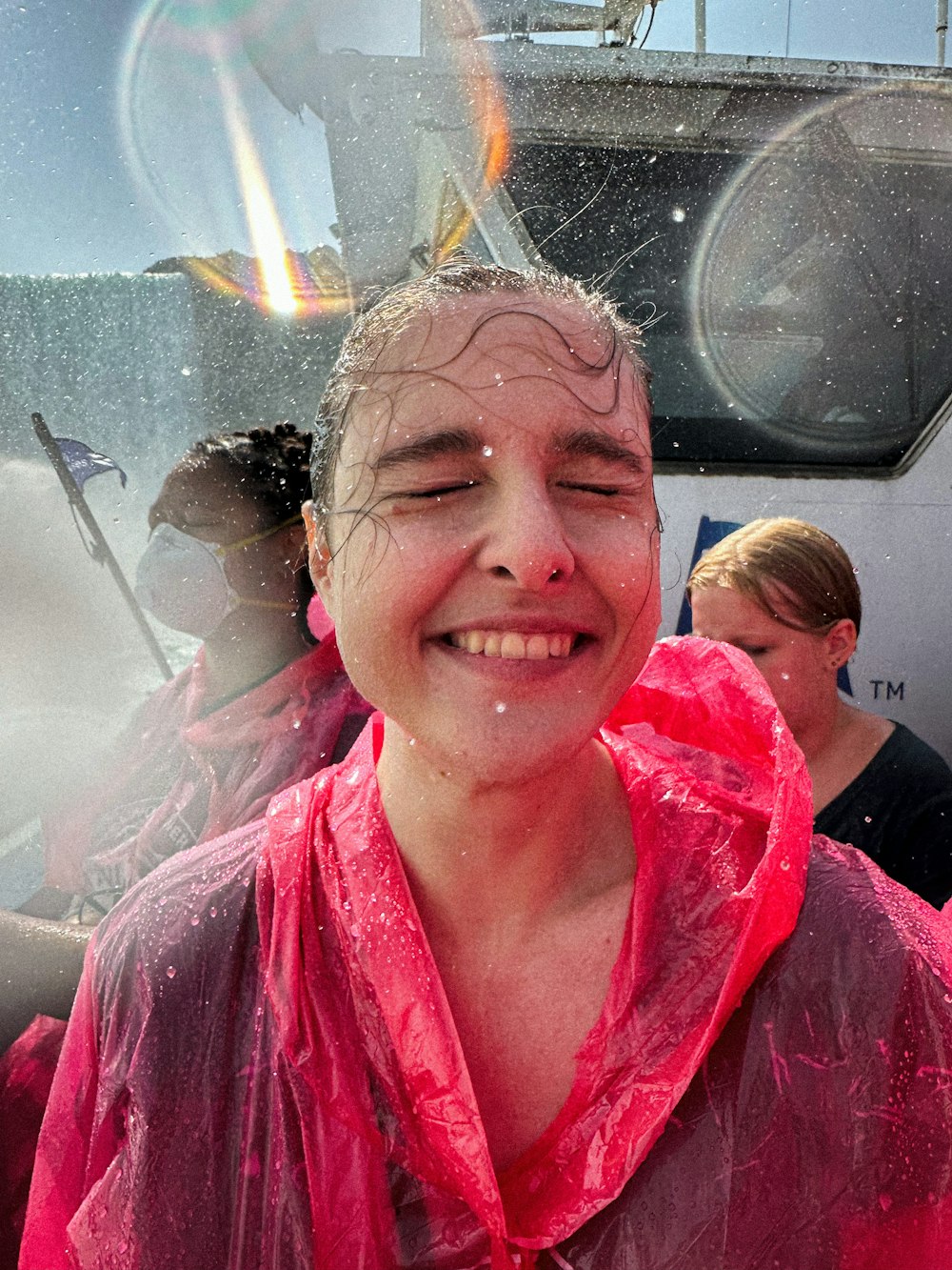 a woman in a pink shirt smiles as she stands in front of a boat