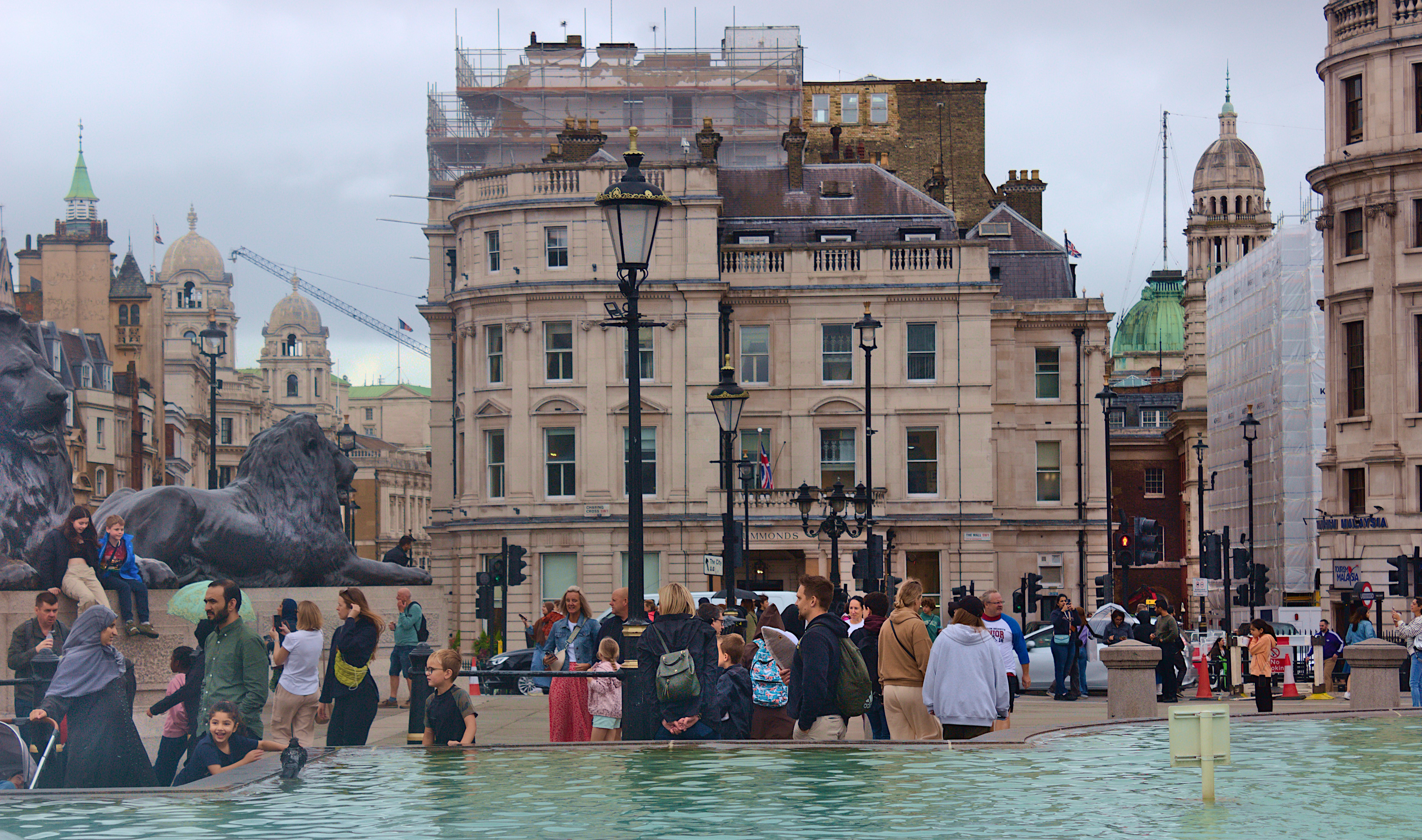 a group of people standing around a fountain in a city