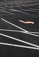 Freshly painted bright white parking lot lines on a smooth asphalt surface under a clear sky.