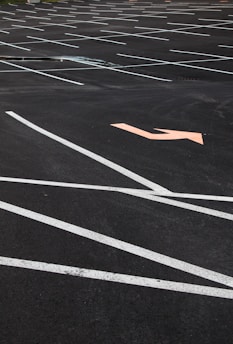 Before and after photo of a freshly painted parking lot line showing clear, bright white markings.