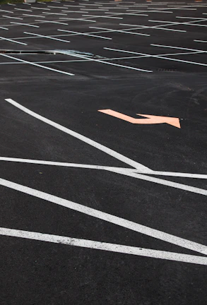 A wide shot of a commercial parking area with newly painted directional arrows and handicap spaces clearly marked.