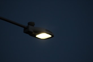Outdoor LED streetlights casting bright white light over a quiet evening street.