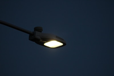 Outdoor LED streetlights casting bright white light over a quiet evening street.