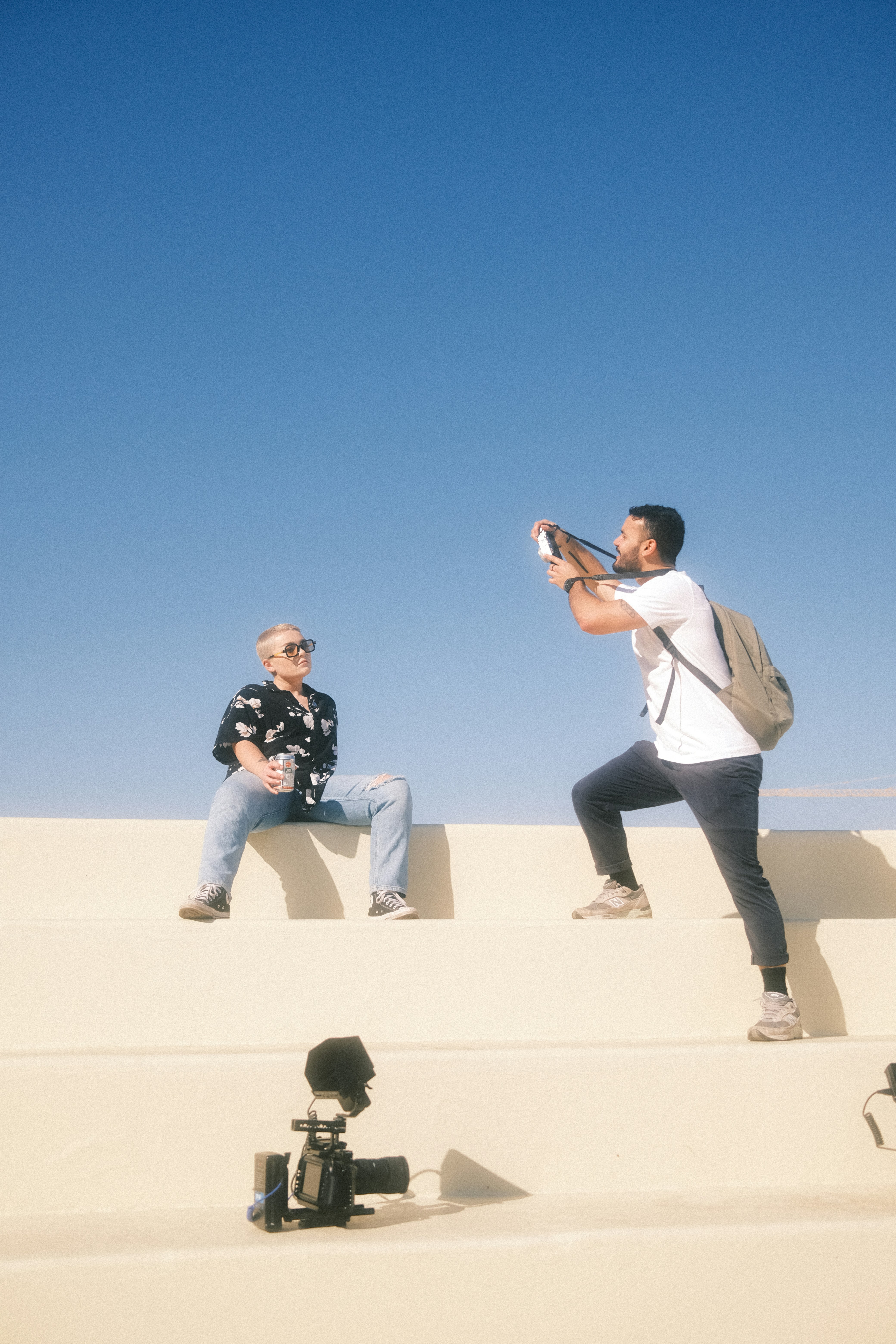 a couple of men sitting on top of a sand dune