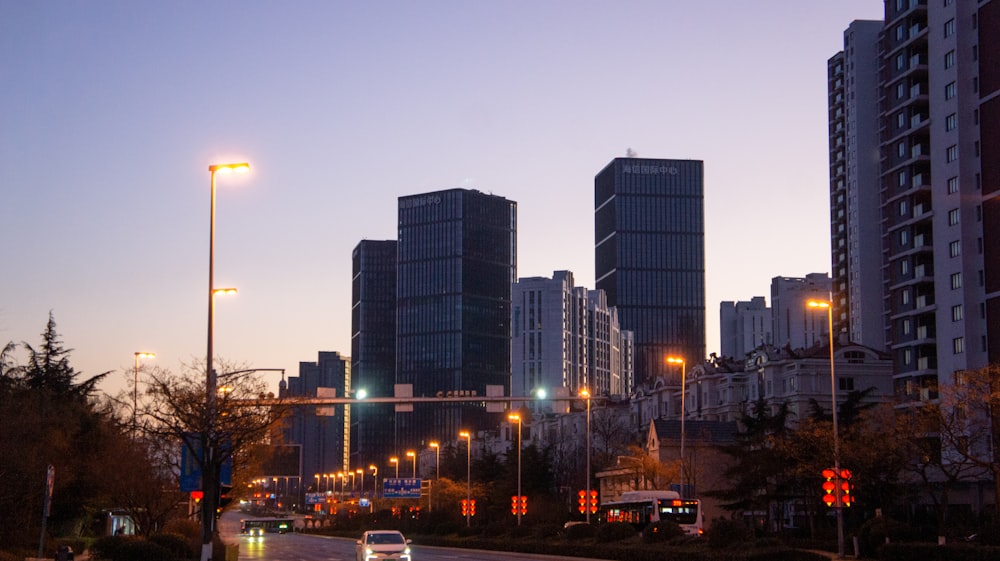 a city street at night with tall buildings in the background