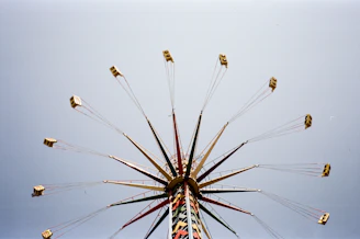 A high-energy shot of a thrill-seeker soaring on a giant swing against a clear blue sky, capturing the rush of adventure.