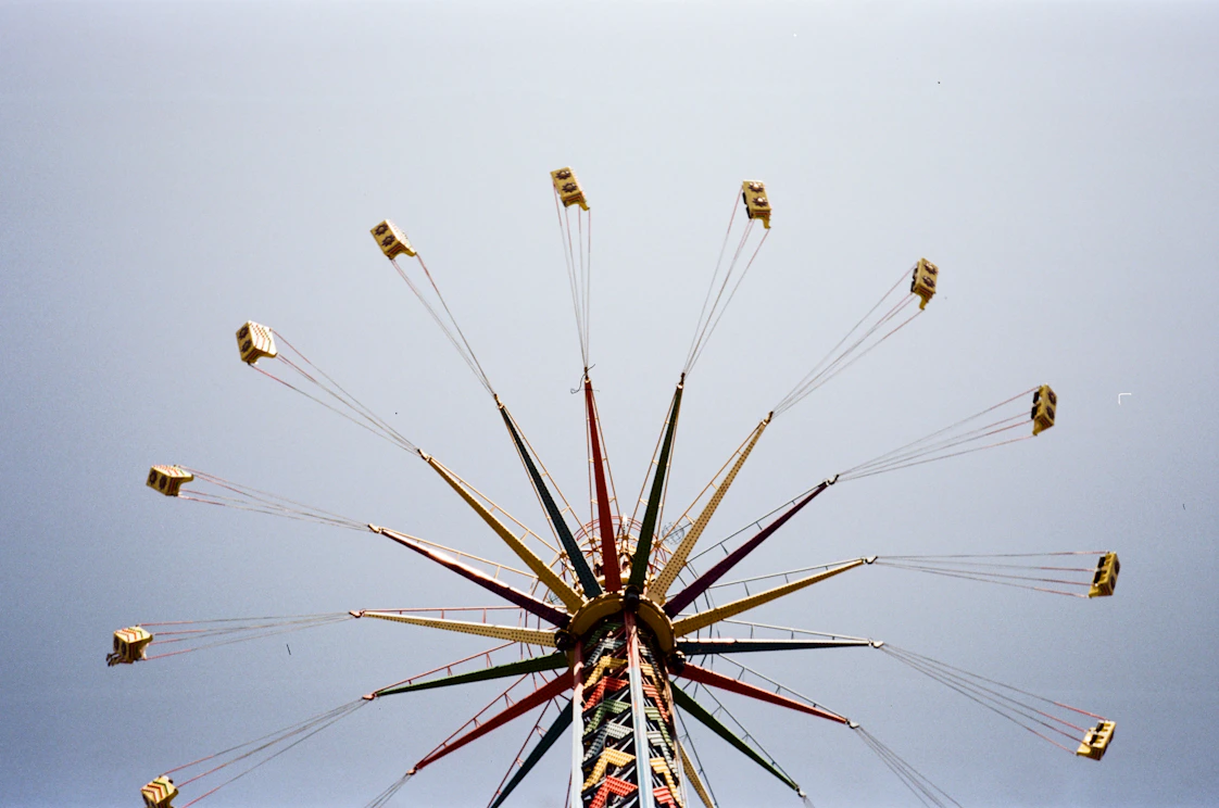 A high-energy shot of a thrill-seeker soaring on a giant swing against a clear blue sky, capturing the rush of adventure.