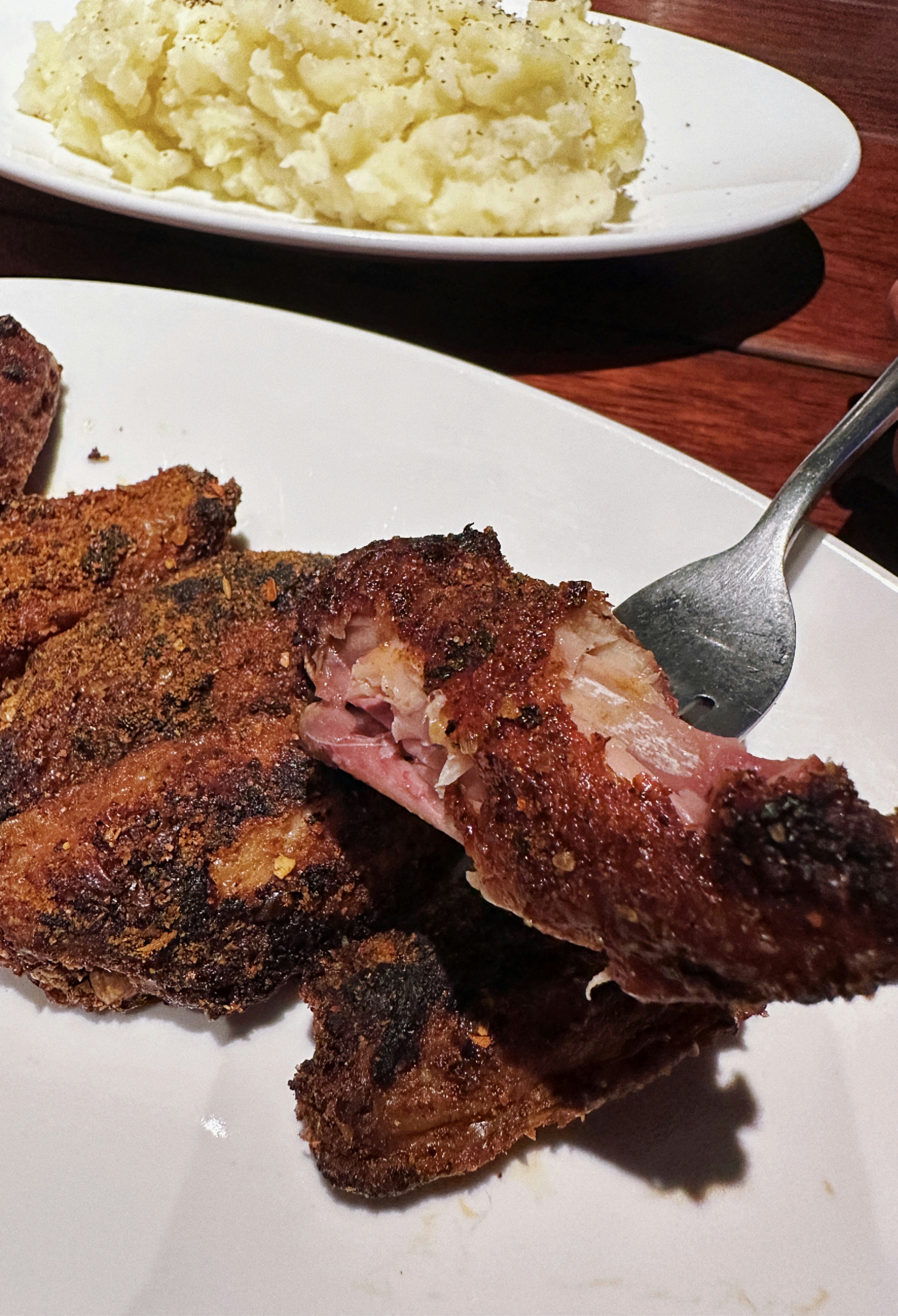 a white plate topped with meat and potatoes