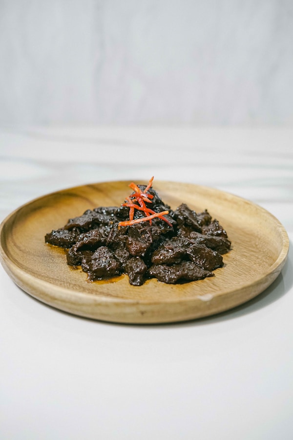 A wooden plate topped with beef and carrots