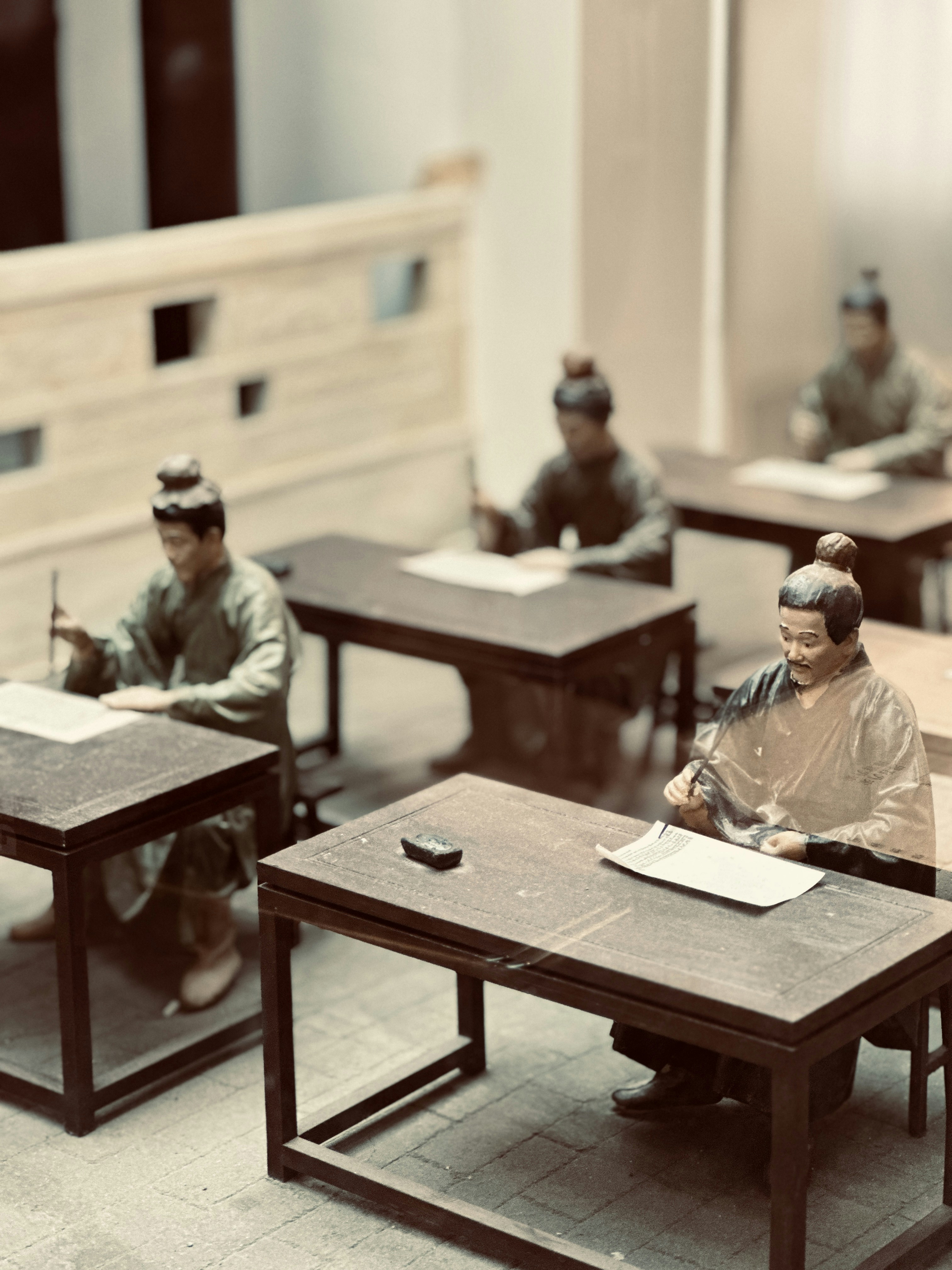 a group of figurines sitting at desks in a room