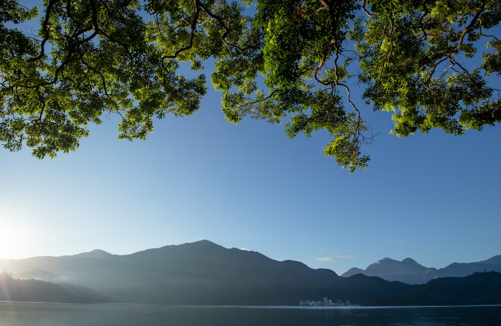 the sun is shining over a lake with mountains in the background