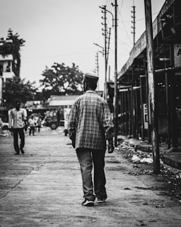 Black and white photo of a person walking through an urban street.