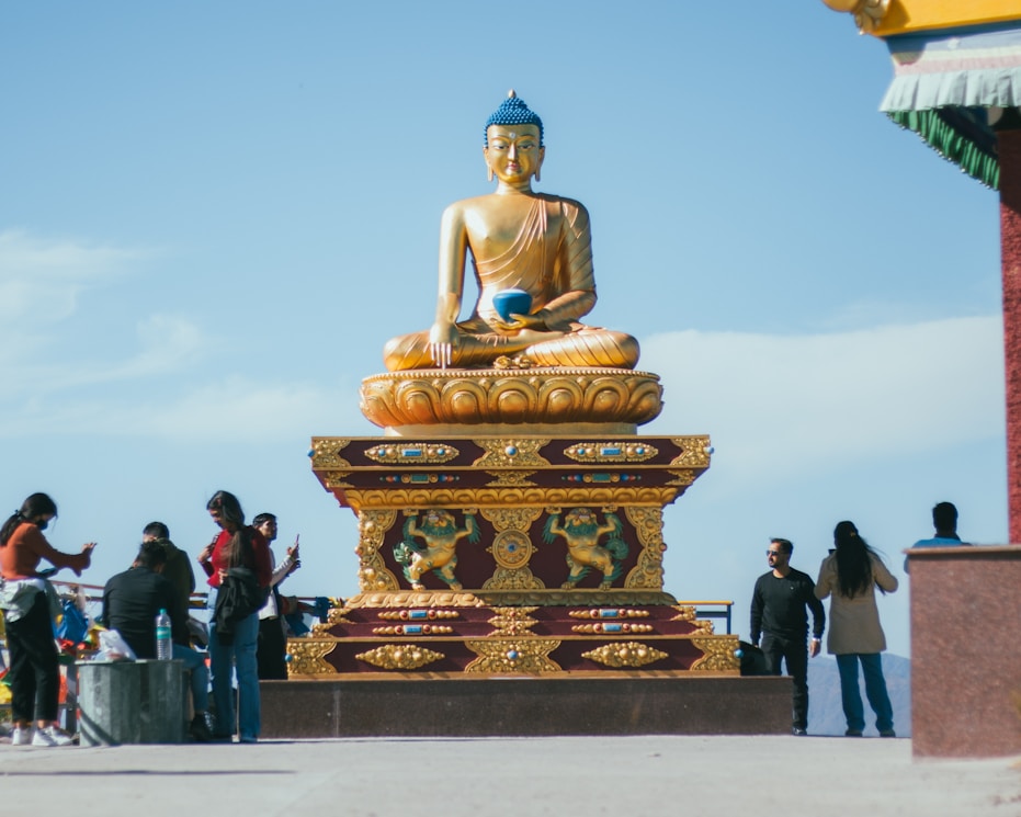 a group of people standing around a golden buddha statue